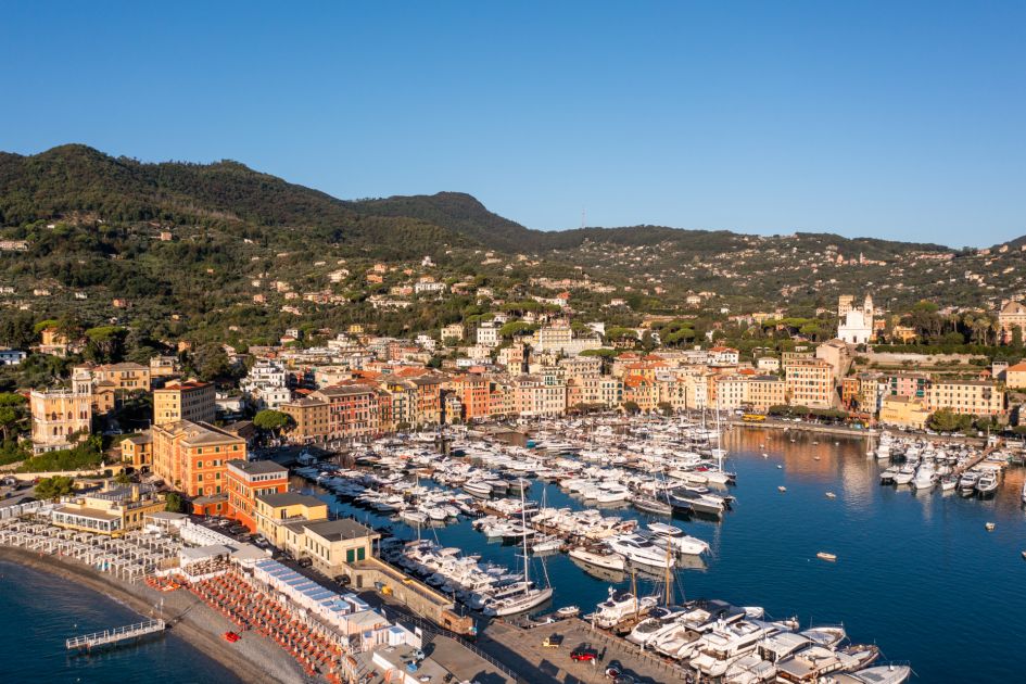 Sunrise over St Tropez bay with luxury yachts docked at the port, and colourful buildings in the background. 