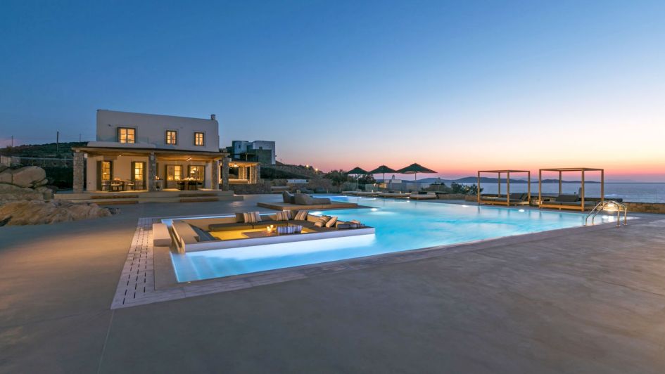 Sunset time at Villa Delphine, one of our top luxury villas in Mykonos. With a stunning shot of the infinity swimming pool in the foreground and the red sky in the background. 