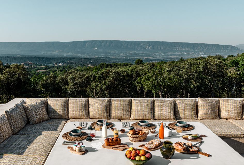 View over the Luberon Valley from Les Hautes de Gordes' main terrace, with an outdoor dining table set for a gourmet lunch. A great option for luxury catered villas in Provence!