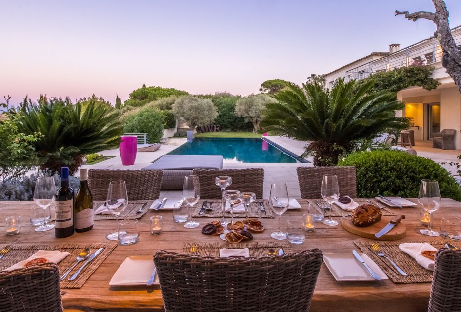 View over the main outdoor dining area of Villa Rêve de Lumière with the outdoor swimming pool and garden in the background. 