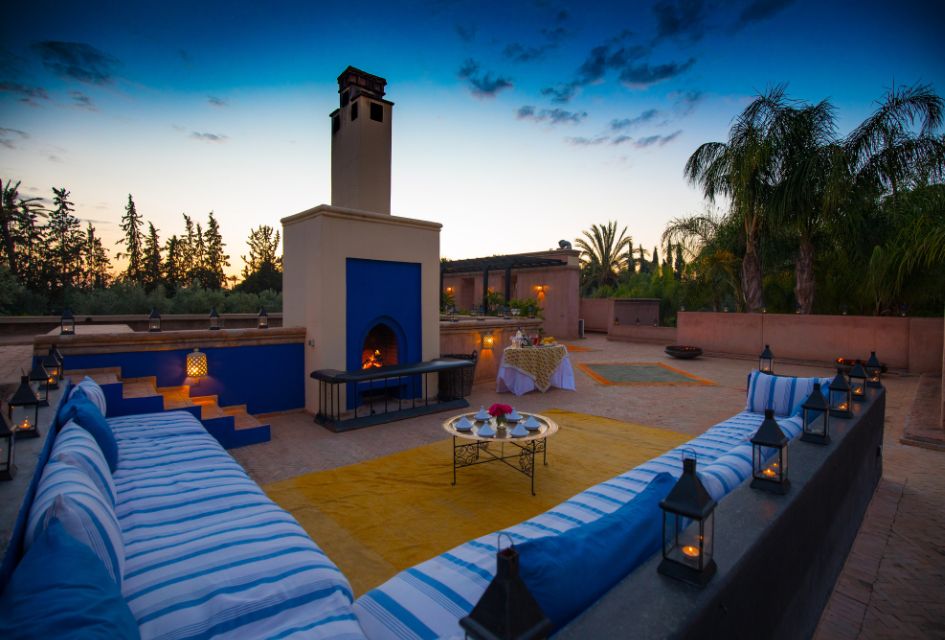 View of the outdoor lounge area of Villa Ezzahra in Marrakech from the rooftop terrace, featuring comfortable sofas and a fireplace.