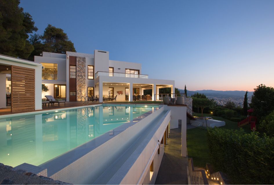 Sunset time at Villa Terra Creta, with the swimming pool in the foreground and the green surroundings and town in the background. 