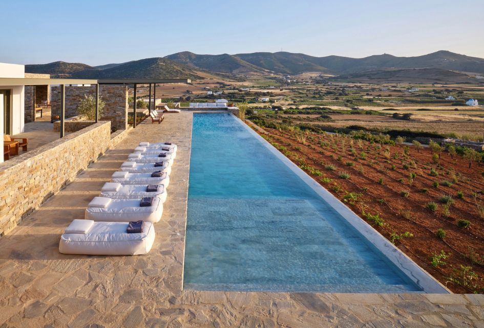 Featured photo of Villa Cezzane's pool terrace, with the infinity swimming pool and sun loungers in the foreground and Antiparos' countryside in the background.