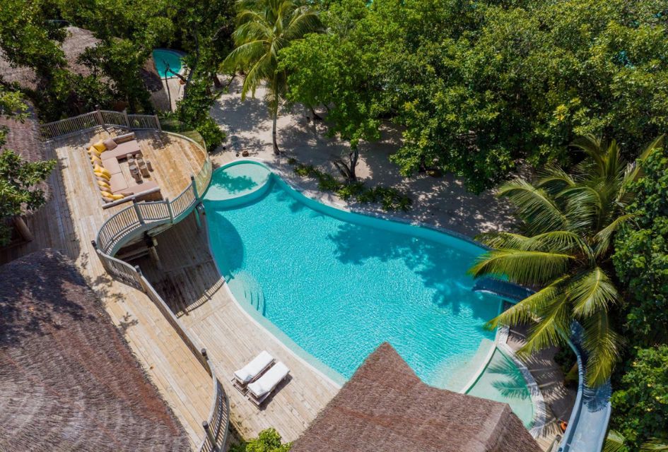 The luxury swimming pool of the Sunset Reserve, a fabulous villa on the Soneva Fushi Reserve in the Maldives, shot from above to showcase the balcony seating as well as the pool slide.