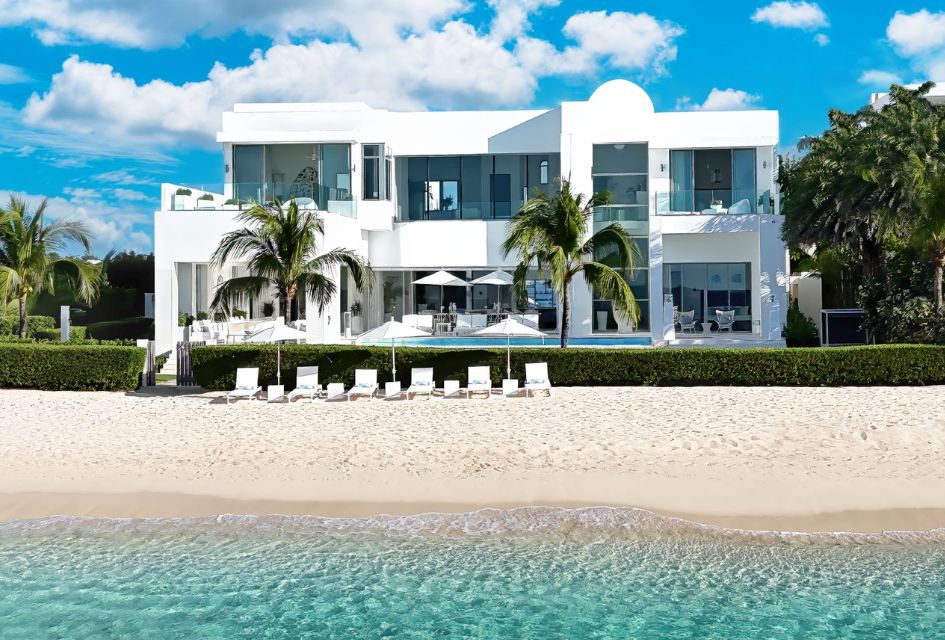 Front shot of The Beach House in Anguilla, with a foreground view of crystal clear waters and golden sands.