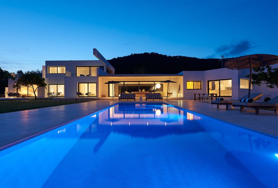 Night view of the large private villa in Ibiza, Villa Can Pegaso Grande, with its infinity swimming pool in the foreground.