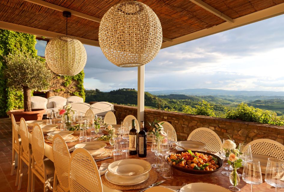 Green rolling hills in the background while on the foreground the alfresco dining area of Villa Il Santo, one of our large luxury villas in Italy.