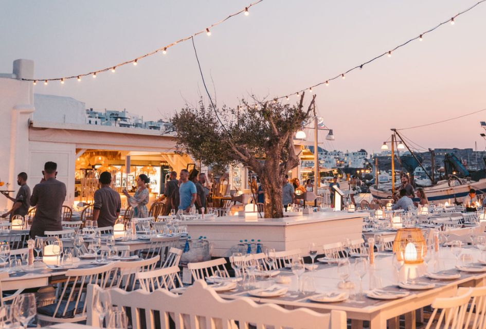 One of Paros' elegant seaside restaurants in the foreground, with boats visible in the background. This is the best island in Greece for an authentic atmosphere! 