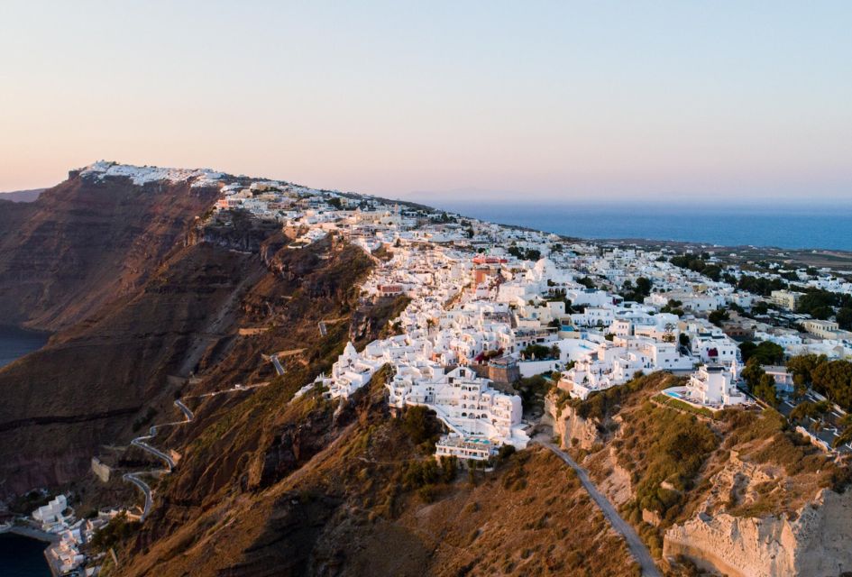 Aerial view over Fira's whitewashed buildings with the caldera visible, a must-visit when enjoying a Greek Island holiday in Santorini! This is the best island in Greece for romantic getaways!